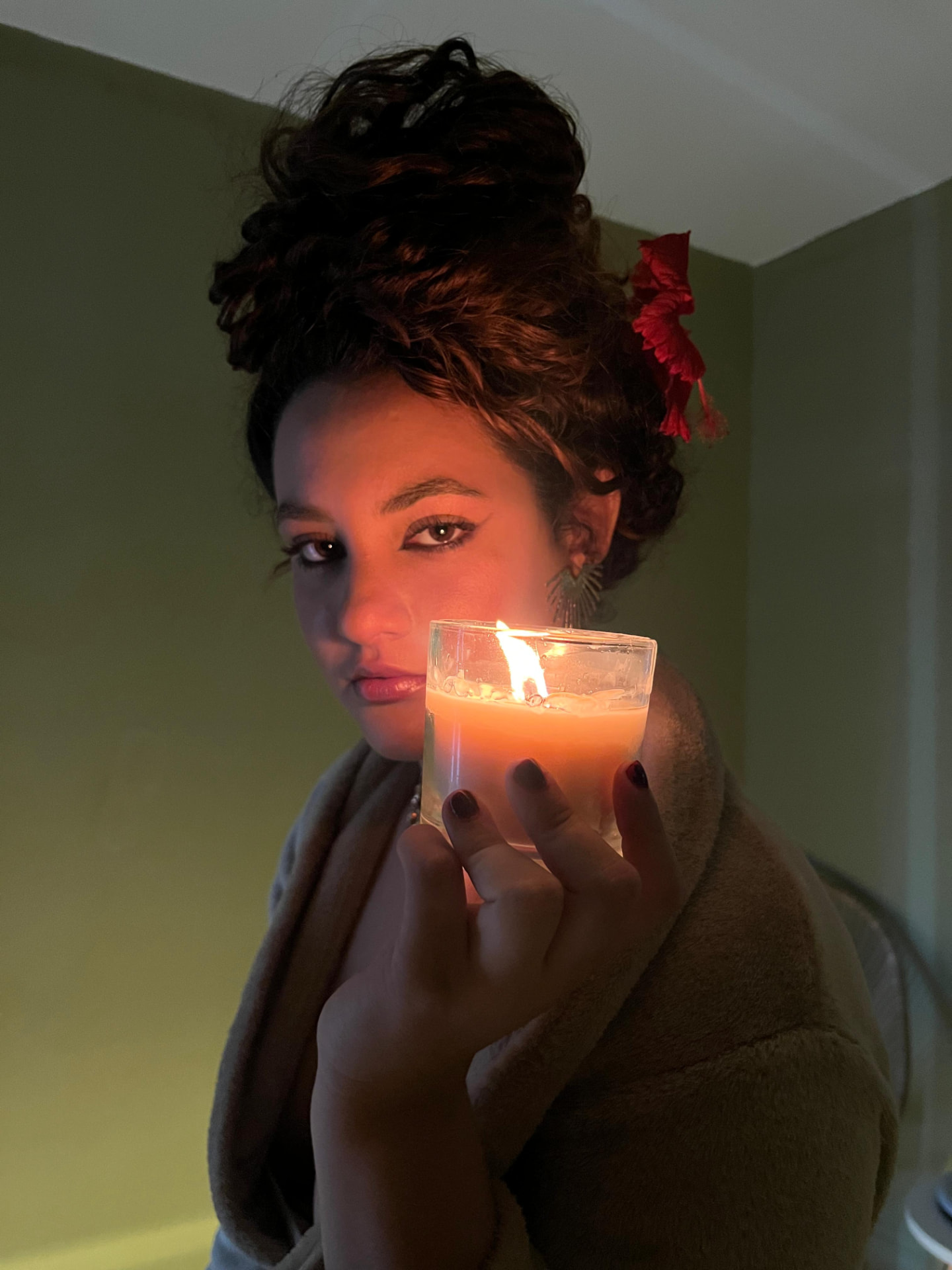 Proprietária da Solei segurando uma vela acesa em ambiente de luz baixa